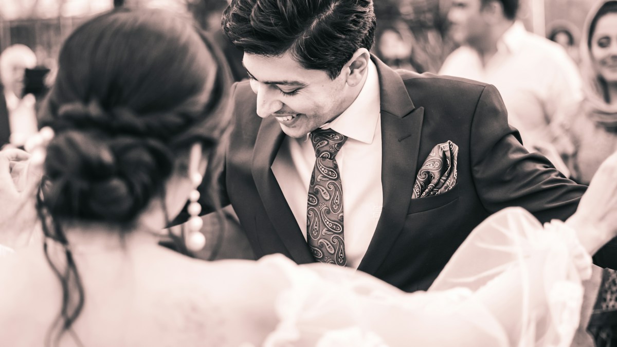 Man wearing a tailored dark suit and tie at an evening reception