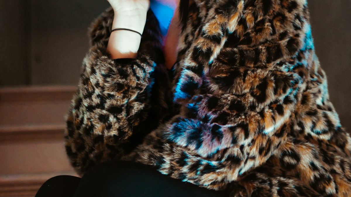Street style fashion detail of a leopard print coat and casual footwear