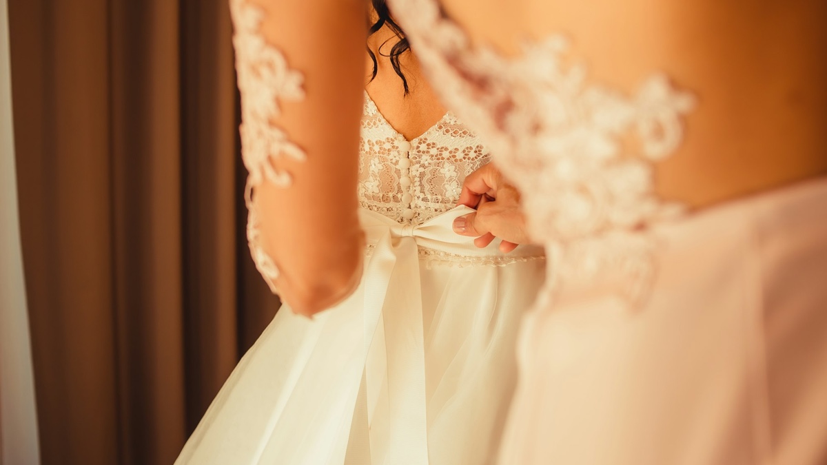 Close-up detail of lace bodice embroidery, buttons and satin ribbon bow on a wedding dress