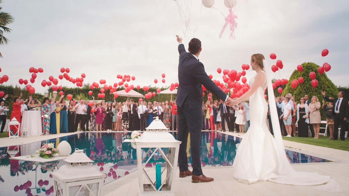Bride wearing an elegant white wedding gown with a train and long veil at an outdoor reception